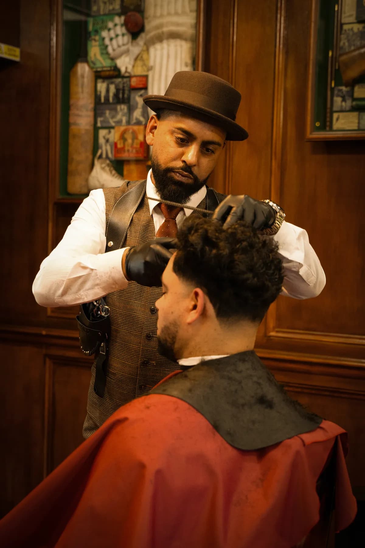 A barber in a pork-pie hat cutting a client’s hair
