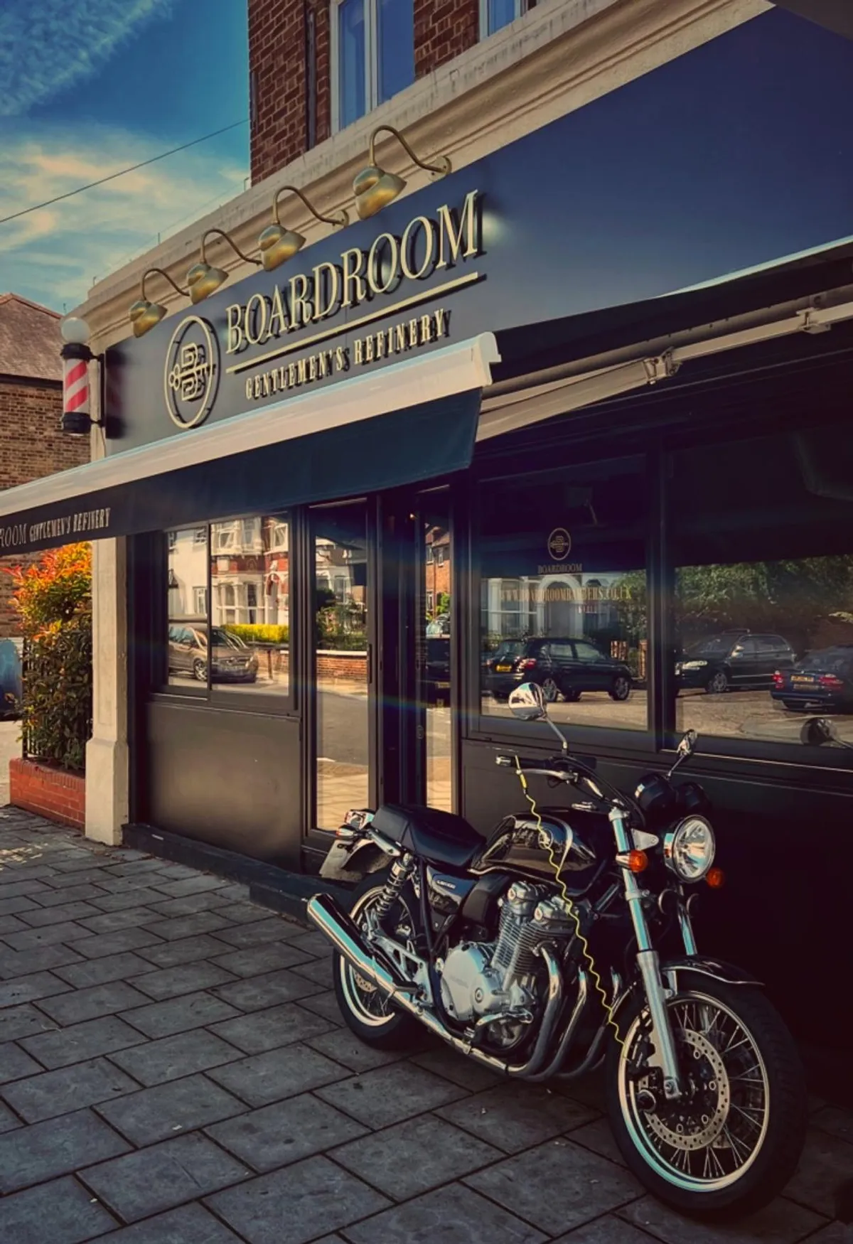The Boardroom shopfront on Ewhurst Road, a motorcycle at the kerb