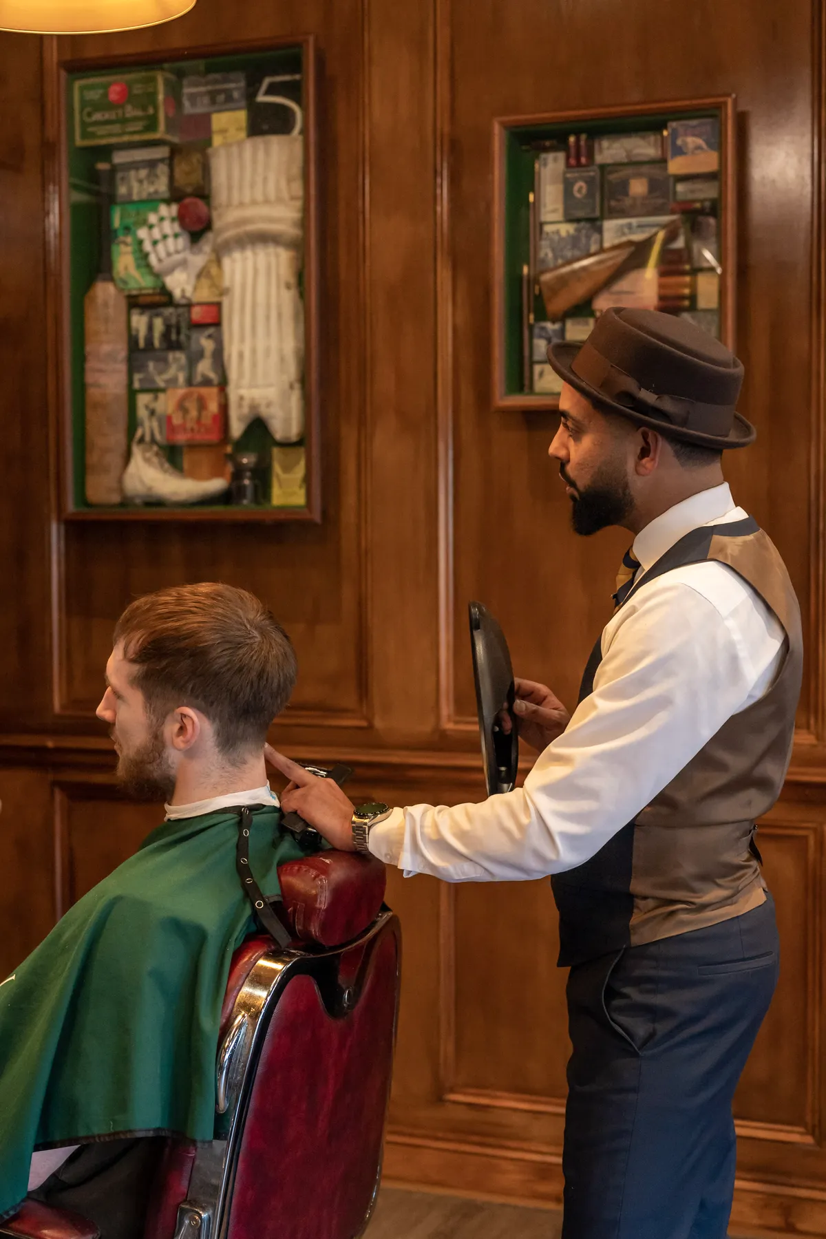 A barber showing a client the finished cut in the mirror